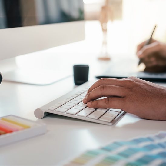 Close-up of email marketing specialist typing on keyboard while using an AI tool