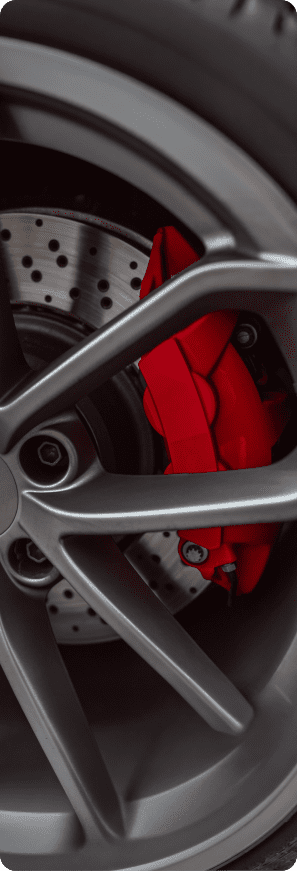 Close-up of a performance car wheel showing a red brake caliper and drilled brake rotor.