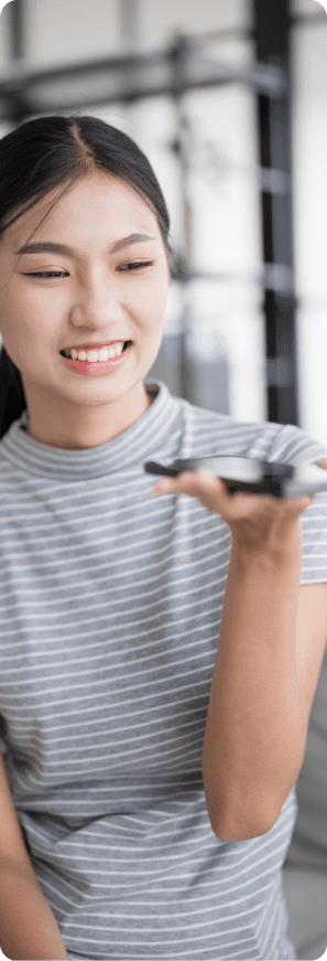 Woman smiling while talking to her smartphone to use ChatGPT in a bright indoor setting.