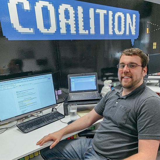 Coalition Technologies team member working at a desk with monitors displaying website content work