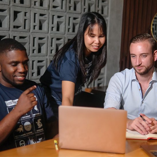 Coalition Technologies team collaborating around a laptop during a project strategy session