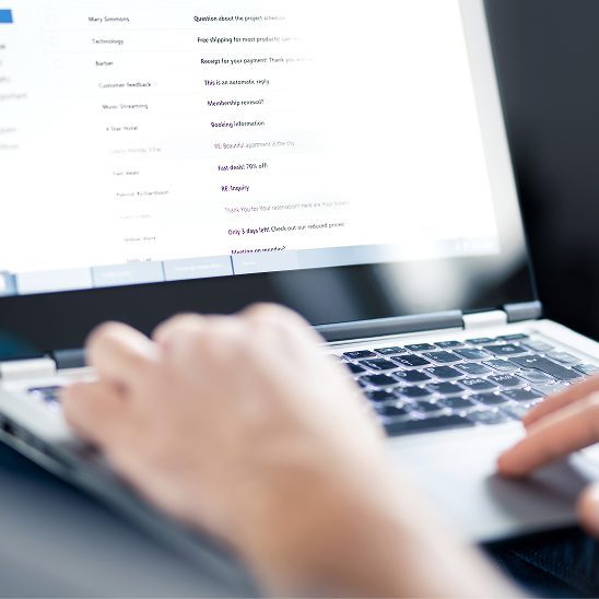 Person typing on a laptop while viewing an email inbox and campaign messages for email marketing