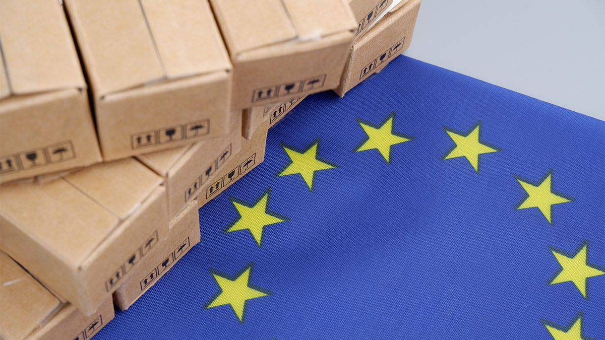 Stacked cardboard shipping boxes resting on a European Union flag.