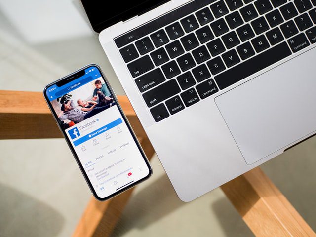 The Facebook app open on an iPhone next to a MacBook
