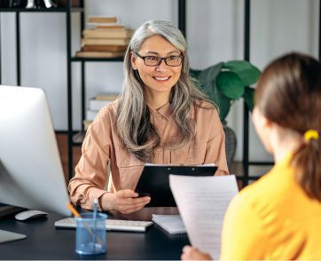 Professional interviewing a google ads candidate at a desk, holding a tablet and reviewing a printed document in an office setting
