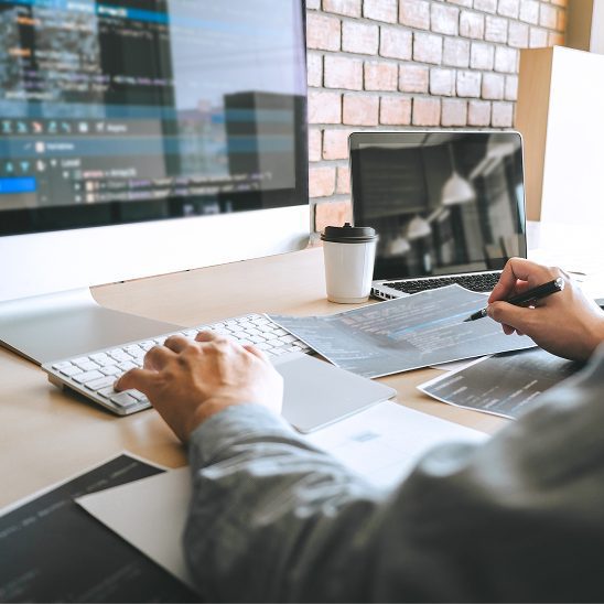 Developer reviewing code and website layouts on a desktop during lead generation web design development