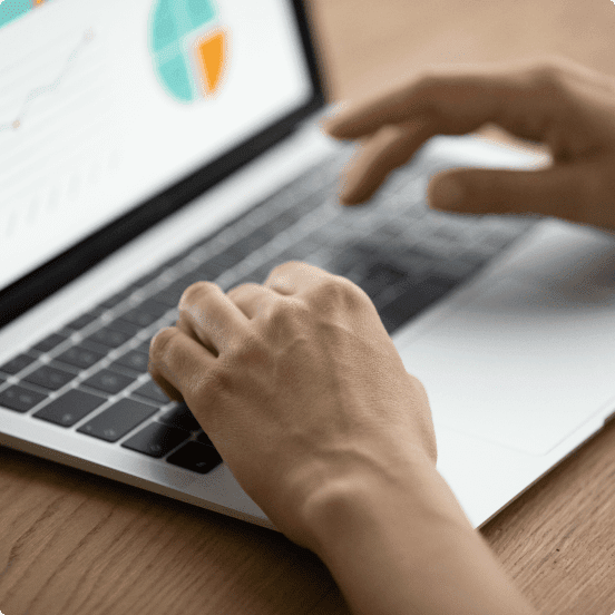 person typing on a laptop with charts on the screen