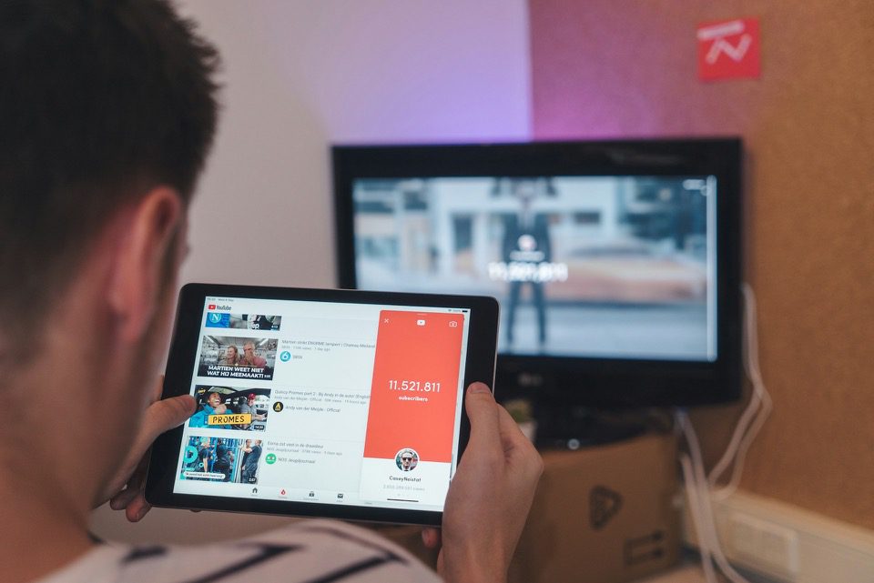 Man Browsing YouTube Videos With Number of Followers Displayed on Screen