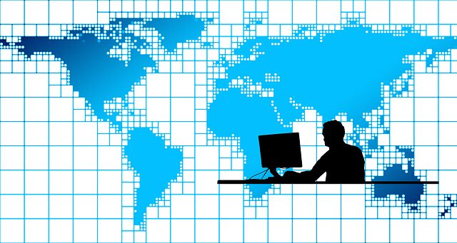 a cartoon image of a man working at a computer in front of a world map