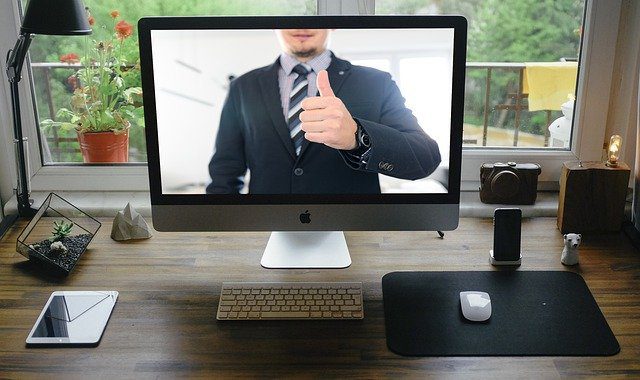 man in suit giving thumbs-up sign during video conference on PC