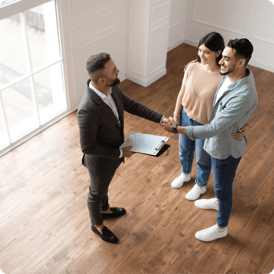 Real estate agent shakes hands with a couple during a home showing.