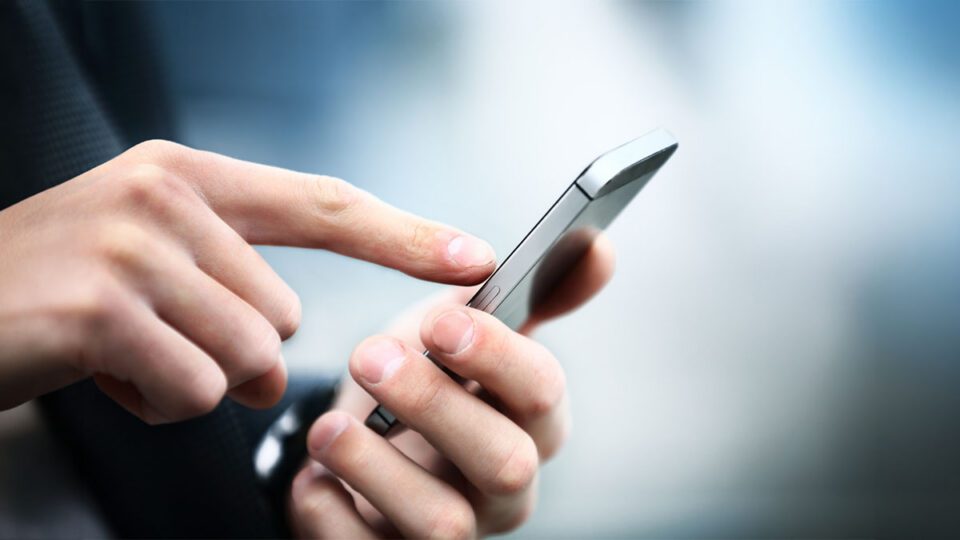 Person using a smartphone with one hand while tapping the screen with the other.