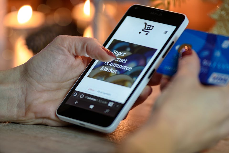 Person Holding Blue Credit Card Shopping on Social Ecommerce on Smartphone
