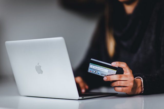 a person using a laptop with a credit card in one hand