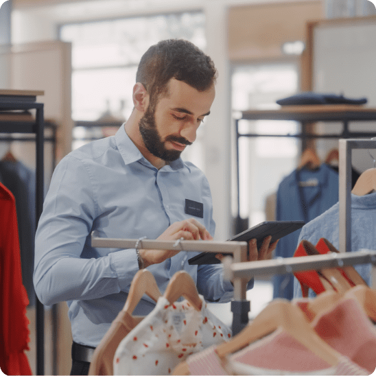 Retail associate using a tablet between clothing racks in a physical store to check retail SEO results.