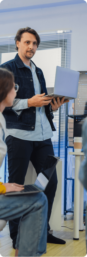 Software team member presents from a laptop during a meeting in a modern office.