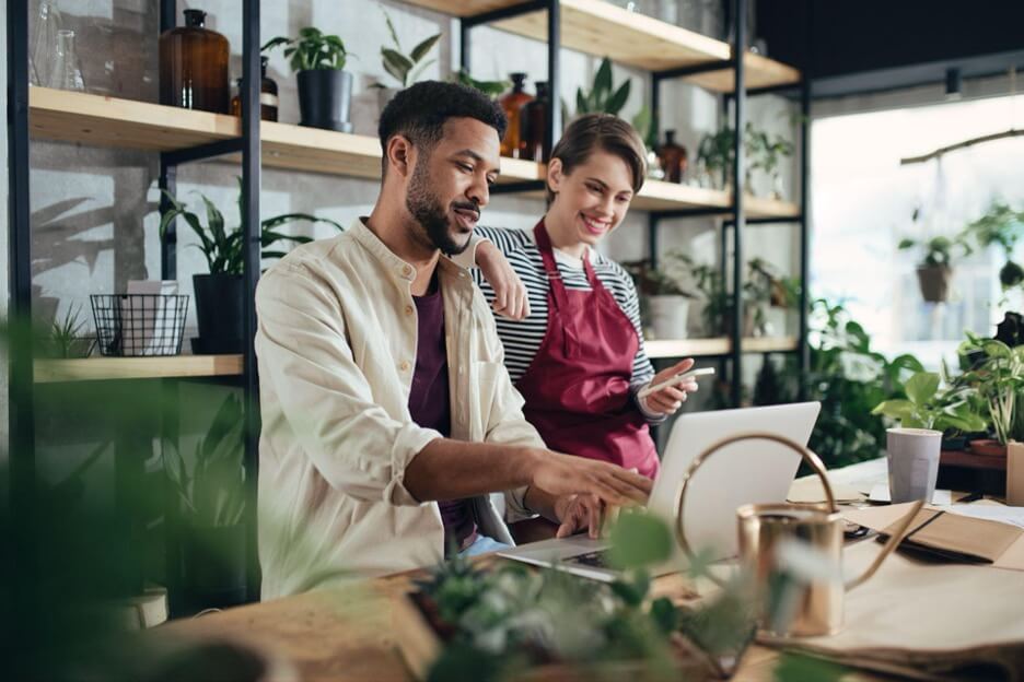 Man and woman working on their small business plant store with a laptop