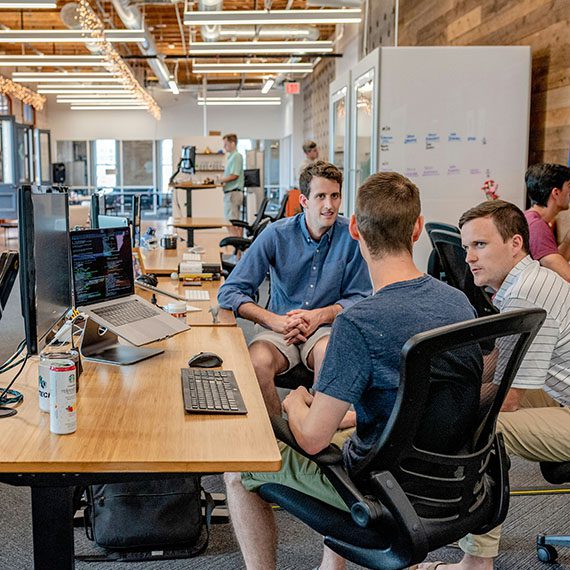 three people sitting next to a long desk