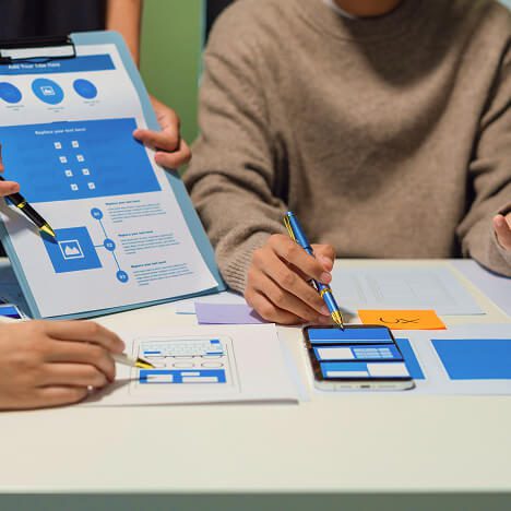 Team members collaborating on mobile app wireframes and user experience layouts during a workshop focused on improving LLM visibility, content discoverability, and AI-friendly digital experiences.