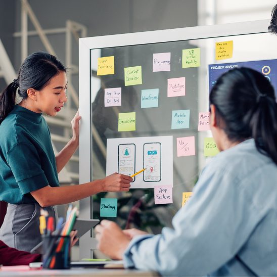 Team presenting website wireframes and interface ideas on a whiteboard during web design planning