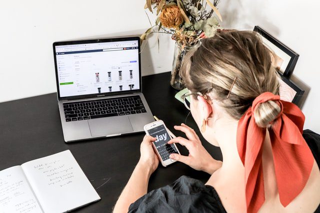 woman with red ribbon browsing ecommerce business via phone and laptop