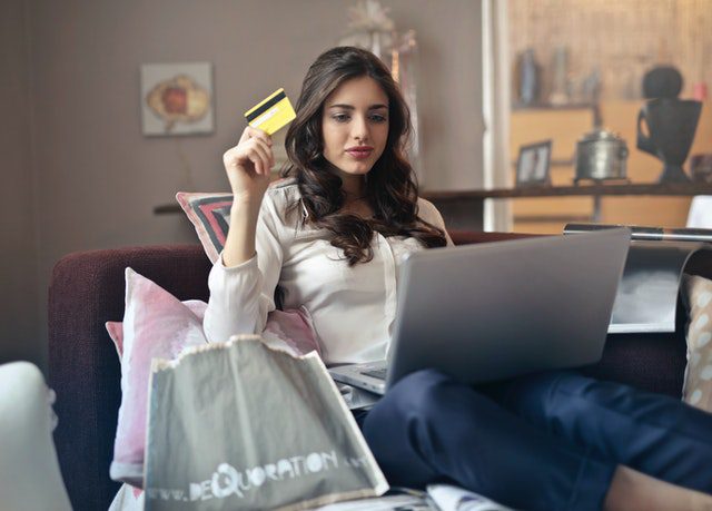 a woman holding a credit card while shopping on a laptop